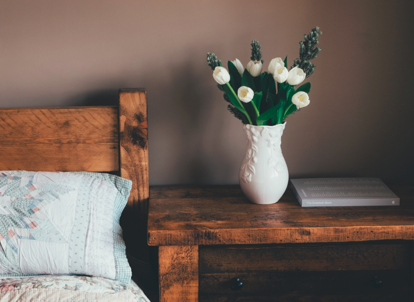 Table de chevet en bois massif avec vase de tulipes blanches dessus